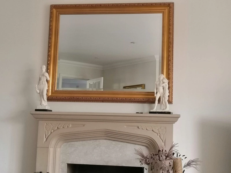 Ornate gilt mirror hung above a fireplace